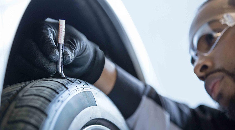 Chevrolet service technician checking tire tread near North Huntingdon PA