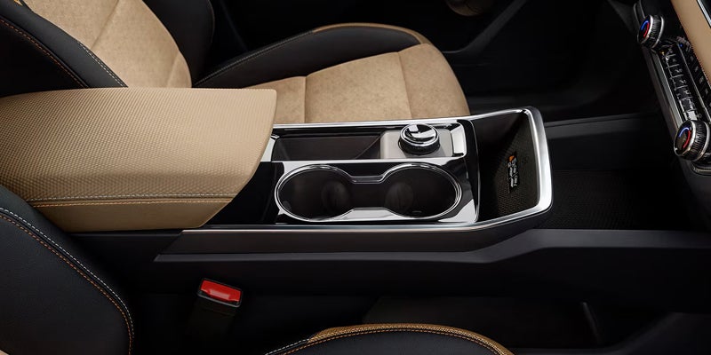 Tan and black front seats, center console and cupholders inside a 2027 Chevrolet Equinox.