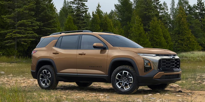 Brown 2027 Chevrolet Equinox shown in side profile beside a wooded area.